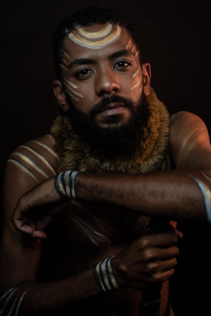 Pensive African male with beard and mustache looking at camera against black background in studio