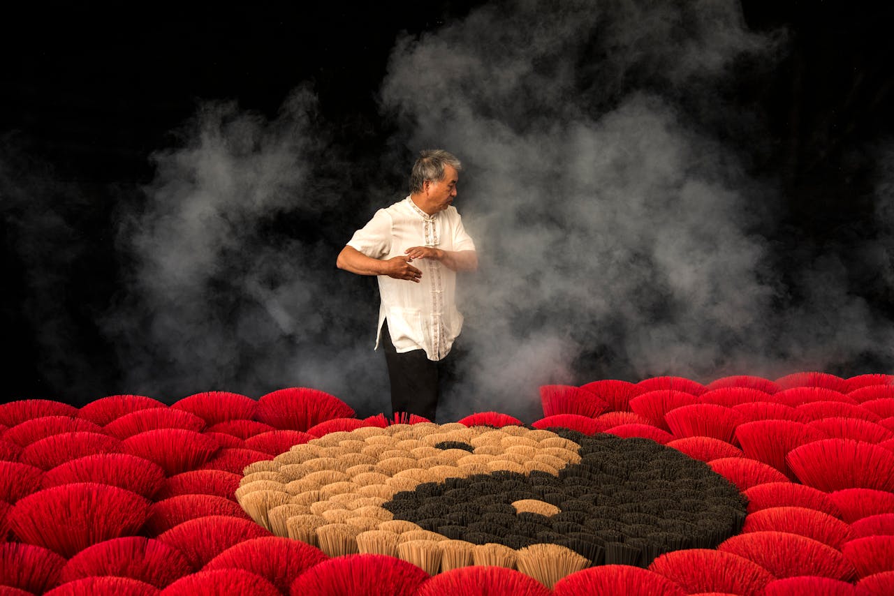 Man standing among colorful incense sticks with smoke in a Taiwan ceremony.